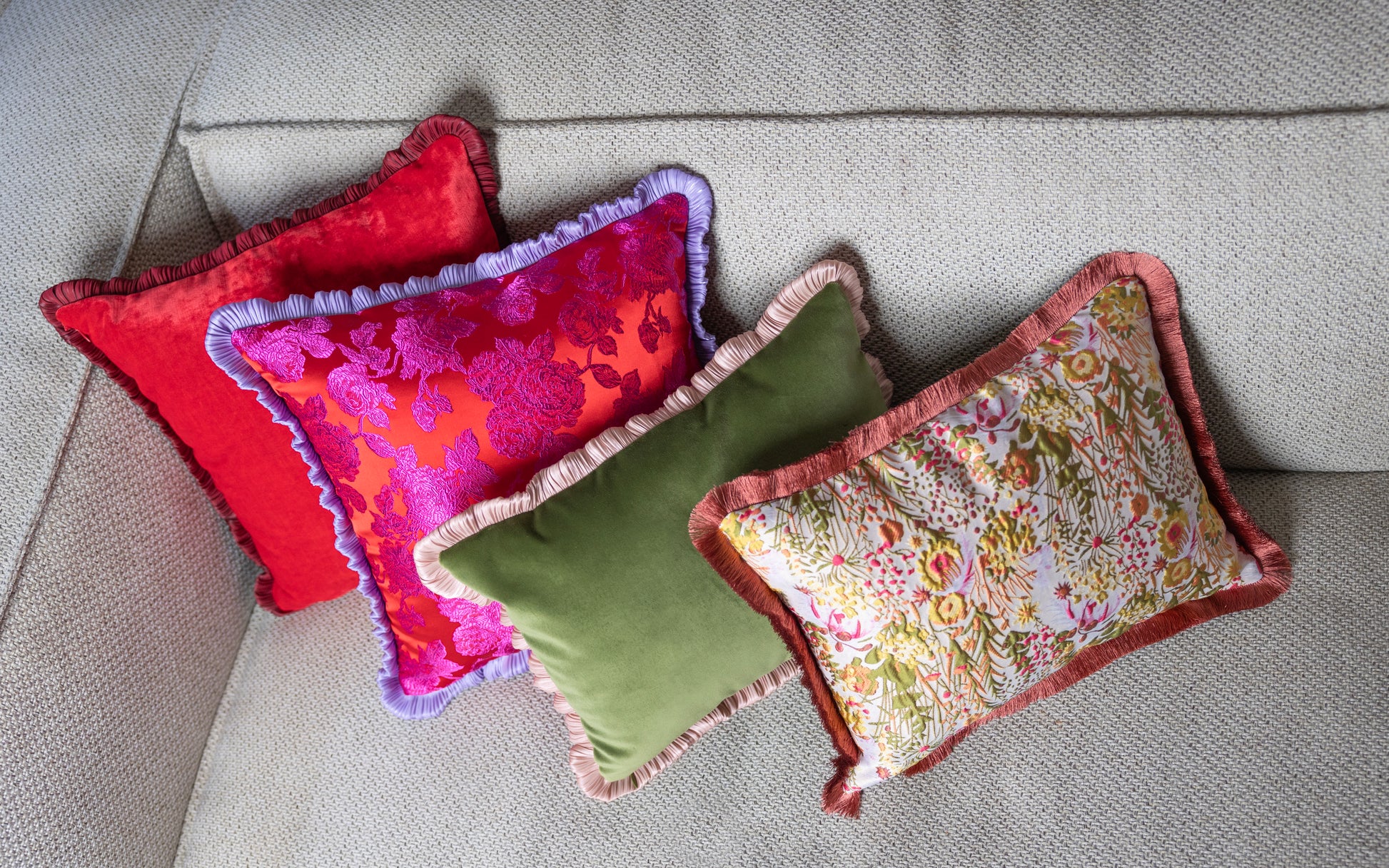 Cojin elegante con una cara de terciopelo verde y la otra con un bordado floral con un fleco al rededor