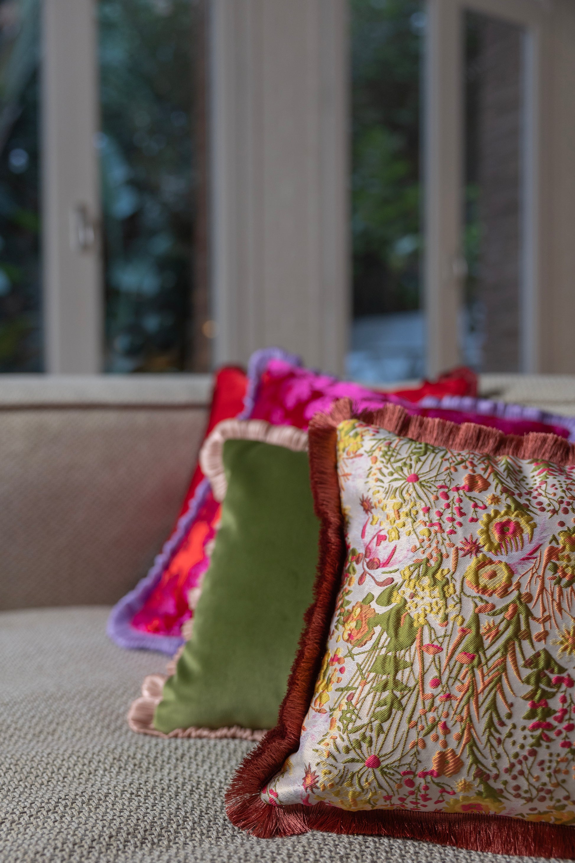 Cojin elegante con una cara de terciopelo verde y la otra con un bordado floral con un fleco al rededor