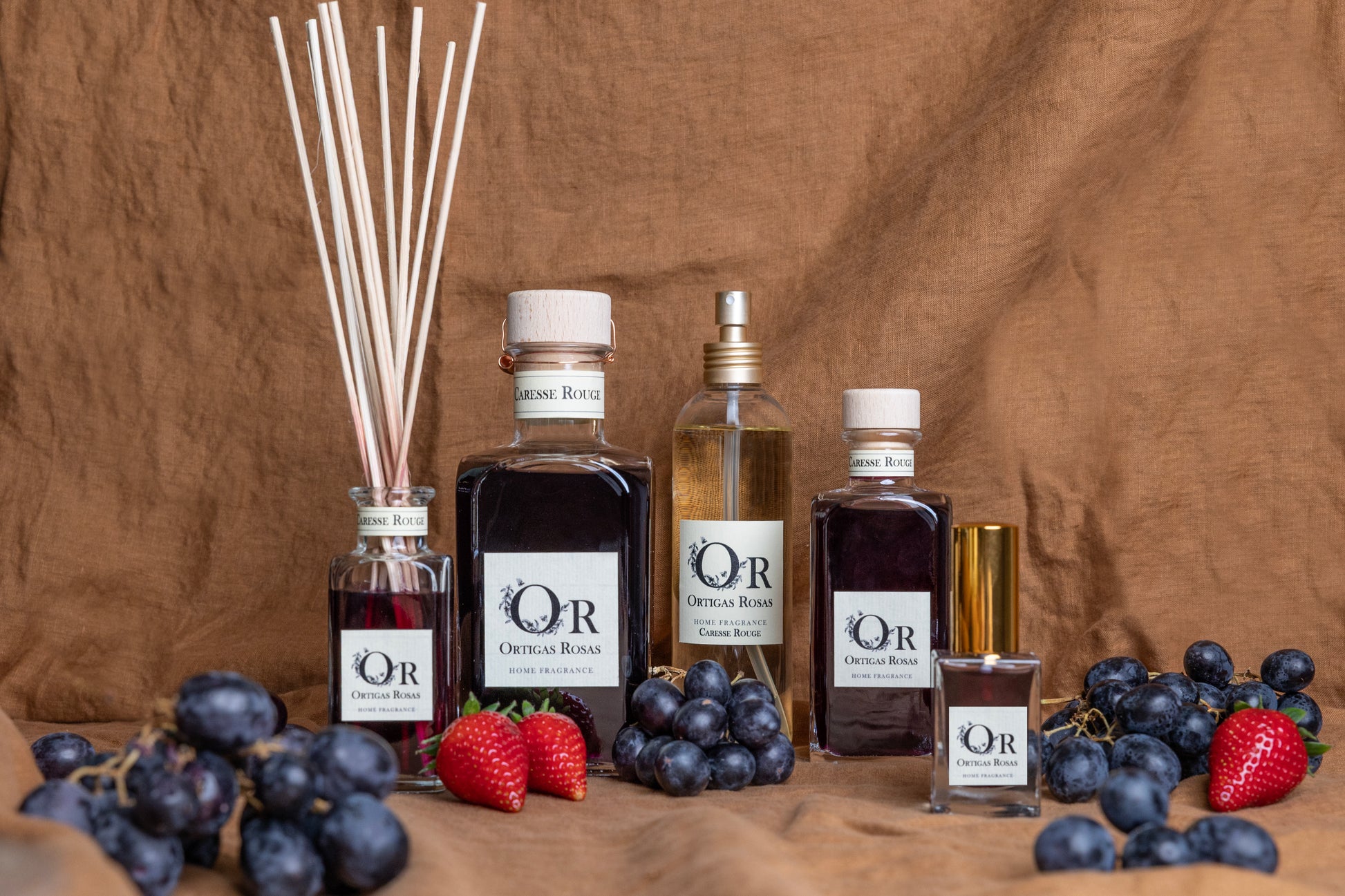 Caresse Rouge es una fragancia para hogar con notas de uva, fresa y cereza, se presenta en un envase transparente con tapón dorado y etiqueta color marfil