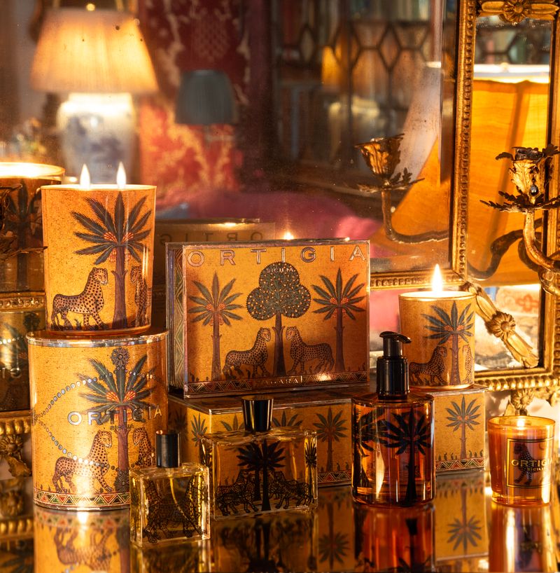 Velas y frascos decorativos de Ortigia Sicilia con diseños de palmeras y animales, en un ambiente cálido y acogedor.