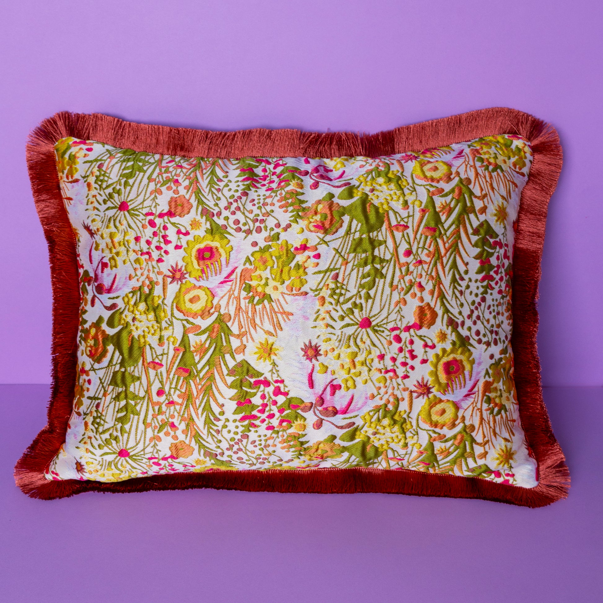 Cojin elegante con una cara de terciopelo verde y la otra con un bordado floral con un fleco al rededor