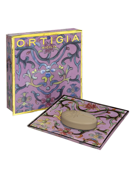 Ortigia sicilia jabon con plato de cristal decorado con flores y fondo color lila y caja decorada con detalles dorados