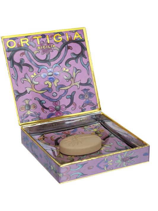 Ortigia sicilia jabon con plato de cristal decorado con flores y fondo color lila y caja decorada con detalles dorados