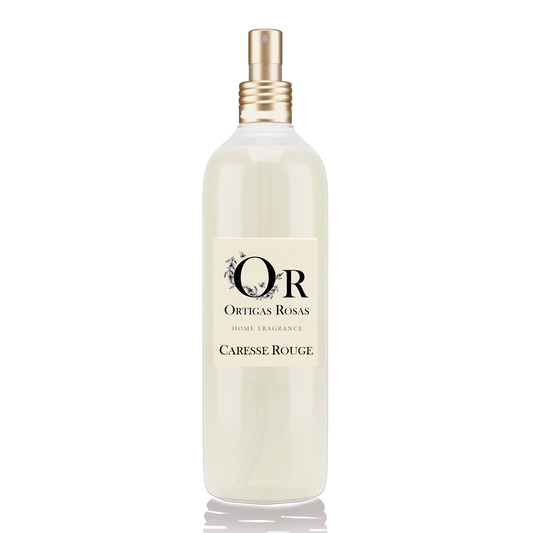 Caresse Rouge es una fragancia para hogar con notas de uva, fresa y cereza, se presenta en un envase transparente con tapón dorado y etiqueta color marfil