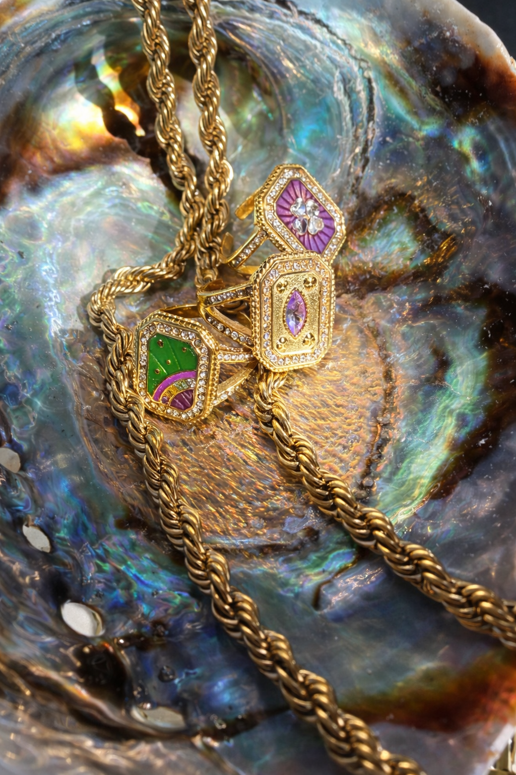 Three rectangular shaped gold rings with gemstones on a textured surface by ortigas rosas