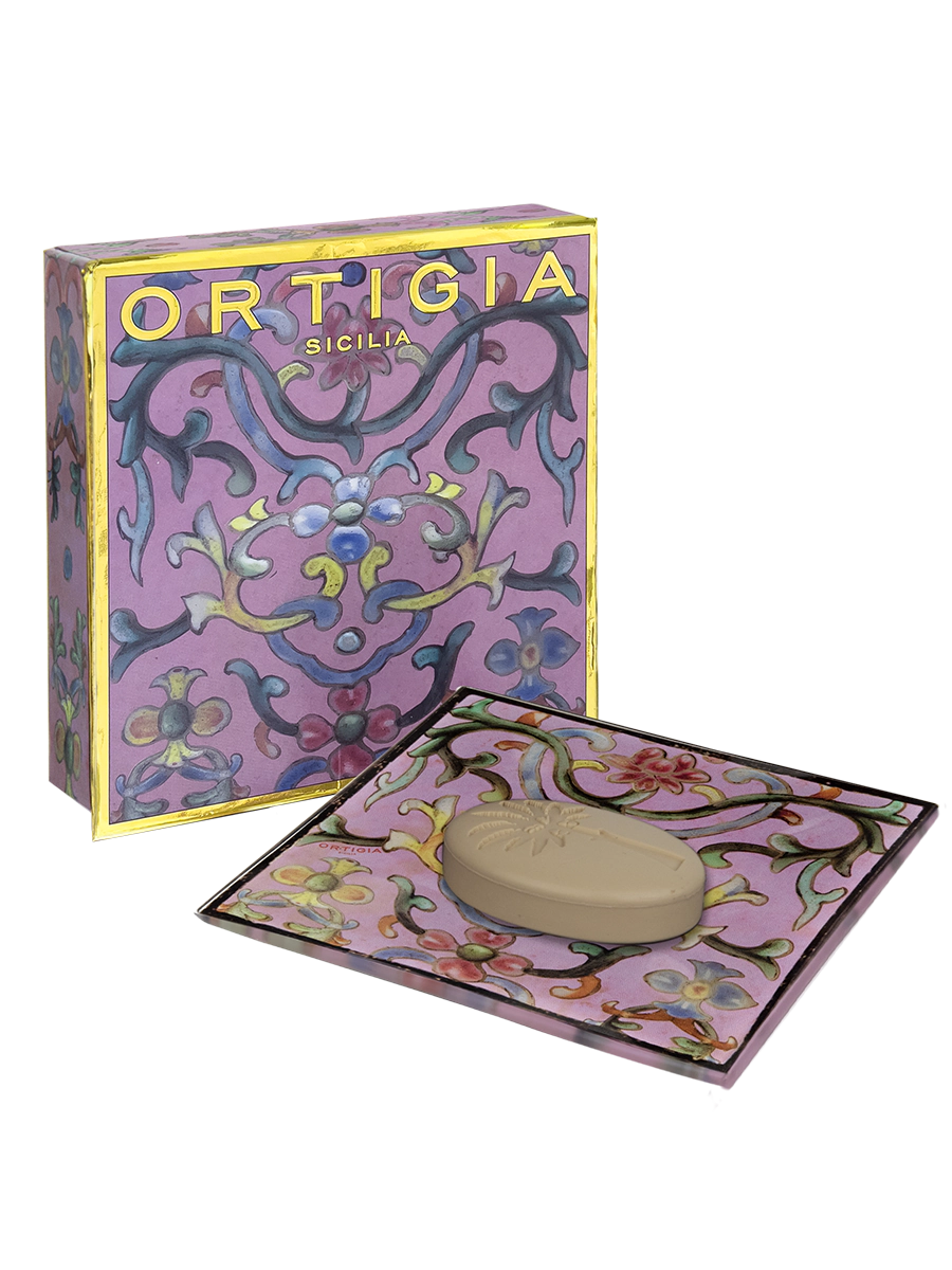 Ortigia sicilia jabon con plato de cristal decorado con flores y fondo color lila y caja decorada con detalles dorados