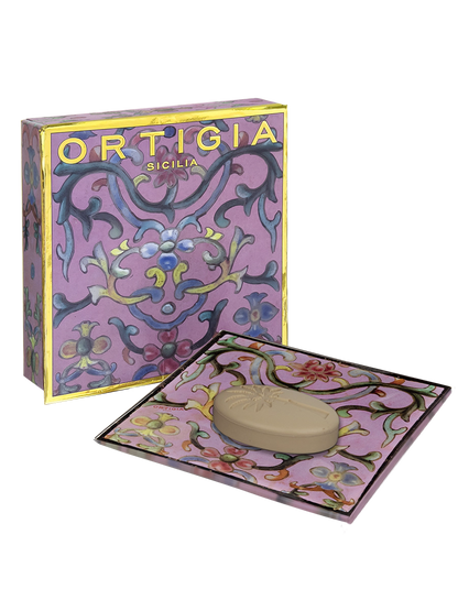 Ortigia sicilia jabon con plato de cristal decorado con flores y fondo color lila y caja decorada con detalles dorados