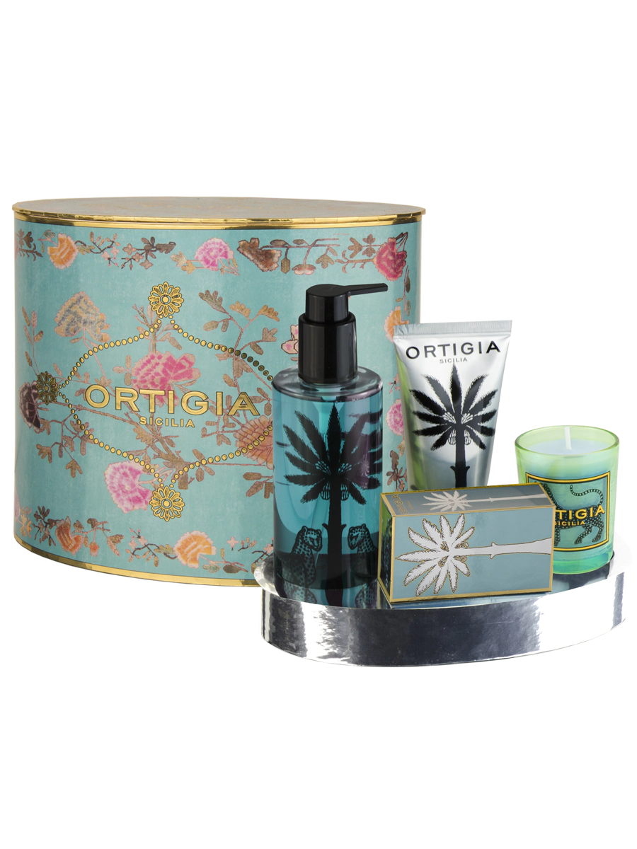 oval set regalo de Ortigia Florio, con caja redonda con fondo color zul claro y flores y ortigia en dorado, jabon liquido color azul claro y decorado con palmera negra y dos leopardos, crema manos color plata y palrmera y vela color azul claro con un leopardo 