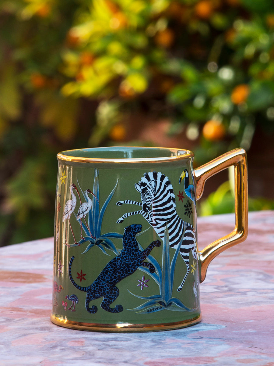 Taza color verde con ilustraciones de animales y asa dorada, con la marca Ortigia y caja cuadrada decorada.