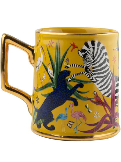 Taza amarilla con ilustraciones de animales y asa dorada, con la marca Ortigia y caja cuadrada decorada.
